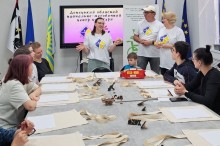 Організатори в білих футболках з логотипом презентують матеріали для майстер-класу