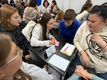 Група учасників працює за столом під час творчого змагання «Мовні перегони».