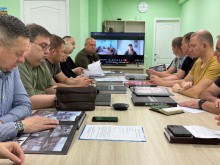 Представники влади уважно розглядають книгу про Донеччину. На екрані онлайн підключення інших учасників наради.