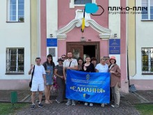 Група переселенців тримає прапор "Гуманітарний хаб "Єднання"