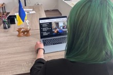 Вигляд з-за плеча пані Антоніни, яка працює за ноутбуком, на екрані відкрито презентацію з заголовком «Кейс: співпраця з Червоним Хрестом»