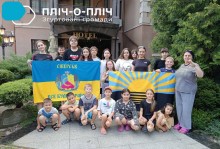 Спільне фото дітей з Сіверської громади біля входу у готель з прапорами Донеччини та Сіверська.