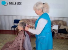 Жінка перукар тримає грибенец у руках яким робить зачіску жінці похилого віку.