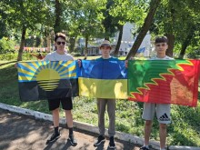 троє хлопців та території табору тримають прапори