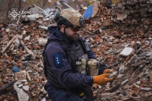 Піротехник ДСНС,стоїть на місці обстрілу, тримає в руках уламок від вибухонебезпечного предмету.