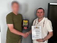Керівник коледжу тисне руку військовому, отримуючи грамоту та пам`ятну табличку за допомогу ЗСУ.