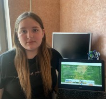Відкритий планшет з віртуальною екскурсією заповідними містами.Школярка поруч посміхається.