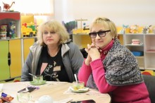 Учасниці зустрічі сидять за столом та уважно слухають.