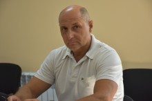 Учасник робочої наради. Сидить за столом.