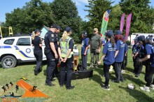 Працівники Національної поліції проводять для джур інтерактивне заняття з безпеки біля службового автомобіля.
