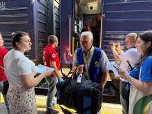 Волонтери допомагають евакуйованим громадянам виносити речі з потягу.