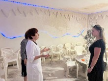 Жінка у білому халаті щось розповідає, біля неї стоять представниці громад. Жінки знаходяться у соляній кімнаті.