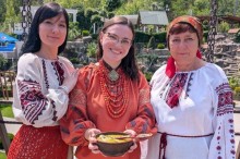 Спеціалісти з НКС в українських вишиванках на вулиці, Людмила Савченко тримає глиняну миску зі стравою