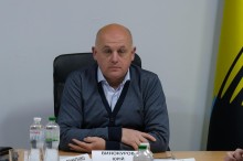 Заступник голови Донецької ОДА Юрій Винокуров, сидить за столом, поруч прапор Донеччини.