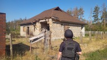 Правоохоронець дивиться на зруйновану одноповерхову будівлю.