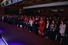 Учасники форуму співають гімн України та тримають руки біля серця.