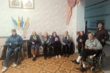 Спільне фото учасників зустрічі, які сидять у кімнаті та тримають у руках виготовлені вироби