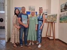 Музейники позують для спільного фото на виставці поруч із картиною на дерев'яному мольберті