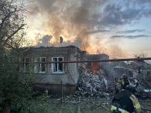 Рятувальник біля будівлі, яку зруйнували окупанти, гасить пожежу