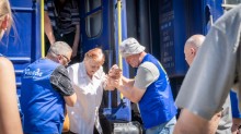 Волонтери допомагають літній жінці вийти з евакуаційного потяга
