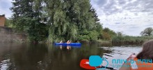 На синій байдарці сидять люди в руках тримають весла.