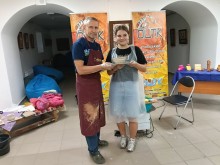 Учасниця гончарного майстер-класу разом із майстром демонструє власноруч створений виріб із глини.