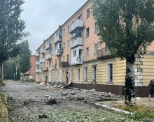 Пошкоджений багатоповерховий будинок та вибиті вікна