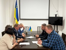 Робоча зустріч двох громад: міський голова Ясінянської громади Андрій Делятинчук із командою та заступник начальника Часовоярської міської військової адміністрації Руслан Прийменко та інші представники громад, сидять за столом.