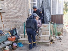 Рятувальники виносять з будинку жінку на кріслі колісному
