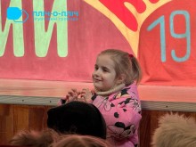 Маленька дівчинка у рожевому костюмі захоплено дивиться на сцену, намагаючись повторювати рухи.