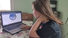 Дівчина працює за ноутбуком, вивчаючи матеріали під час Обласної екологічної експедиції, сидячи за столом удома.