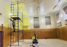 Ремонт спортивної зали у школі для дітей Донеччини. Стіни будівельники фарбують у жовтий колір.