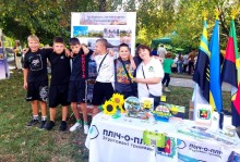 Спільне фото дітей на фоні стенда з фотографіями Торецької громади. На столі сувенірна продукція.