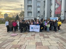 Спільне фото дітей, біля фасаду будинку. Попереду тримають прапор з логотипом проєкту Пліч-о-пліч.