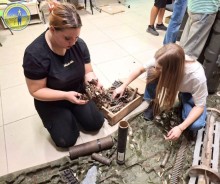 Дві дівчини на підлозі розглядають патрони та снаряди.