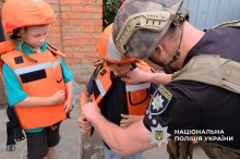 Поліцейський допомагає дітям вдягнути бронежилет