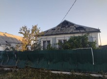Пошкоджений вибухом паркан та будинок з вибитими шибками та руйнуваннями покрівлі.