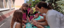 Психологи біля столу показують дітям  як наповнити повітряні кульки