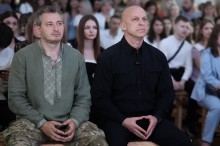 Вадим Філашкін сидить поруч із українським музикантом Колею Серьгою на святковому заході.