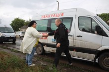 Жінка та чоловік вітаються на фоні евакуаційного автомобіля