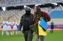 Захисник з нареченою та букетом троянд виходять з поля