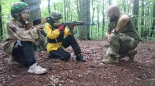 інструктор проводить заняття зі стрільби для учасників табору, навчаючи правильному положенню тіла та техніці прицілювання.