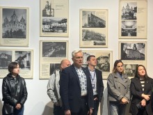 Відвідувачі виставки слухають виступи на тлі стіни з архівними чорно-білими фотографіями