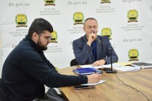 Ігор Бойко та представник адміністрації сидять за столом та уважно слухають доповідь.
