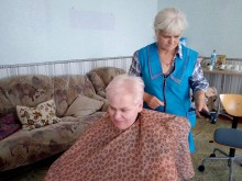 Жінка з укладкою волосся, посміхається. Перукар збирає інструменти для зачісок