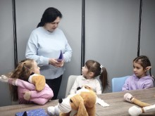 Педагог спілкується з дівчатками, які обіймають своїх песиків Хібукі, отримуючи емоційну підтримку в межах проєкту «Теплі обійми»