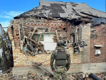 Правоохоронець стоїть біля зруйнованої окупантами будівлі