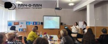 Представники громад,сидять за столом на уважно дивляться на екран монітора.