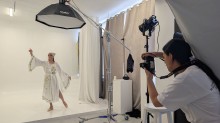 Фотограф знімає модель в українському етнічному вбранні, яка позує з піднятими руками