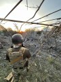 Військовий стоїть на фоні будівлі, яку знищили окупанти обстрілом.
